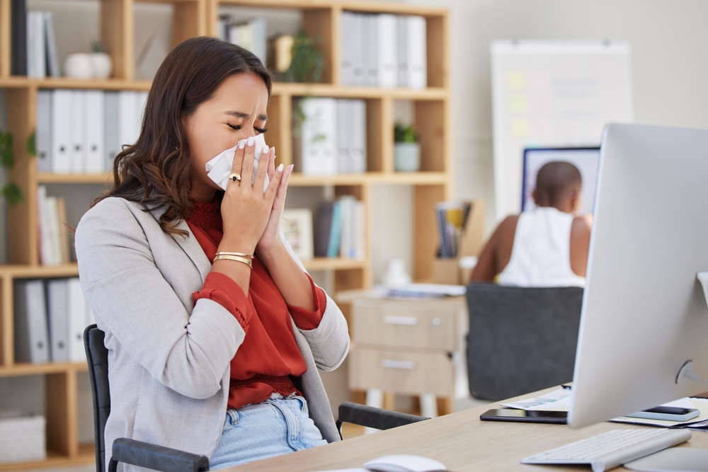 woman blowing nose in office