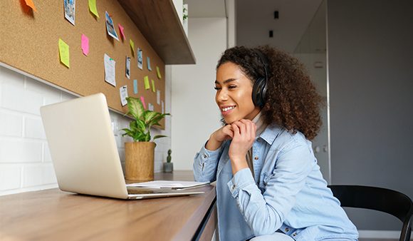 Woman smiling at laptop with headphones on