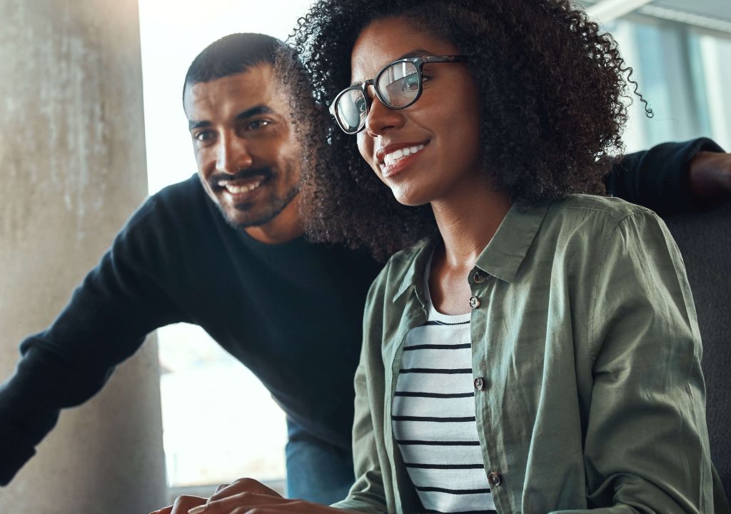 man and woman looking computer smiling