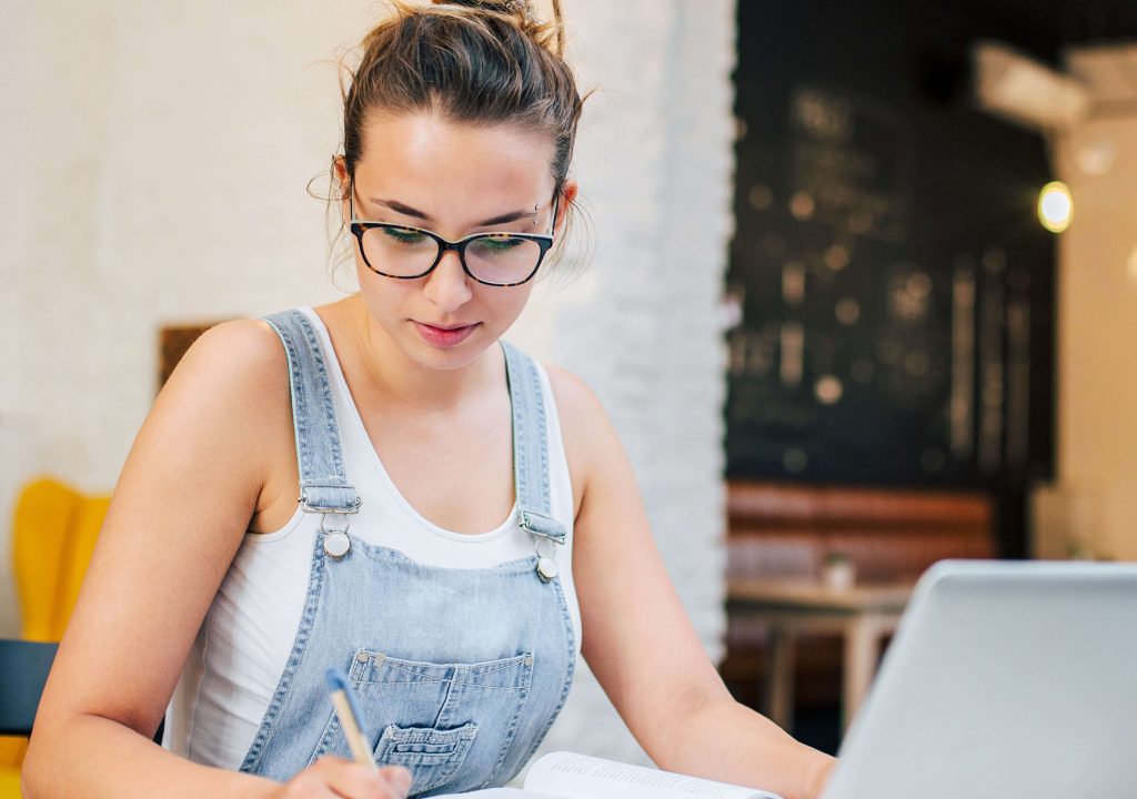 woman taking notes with open book