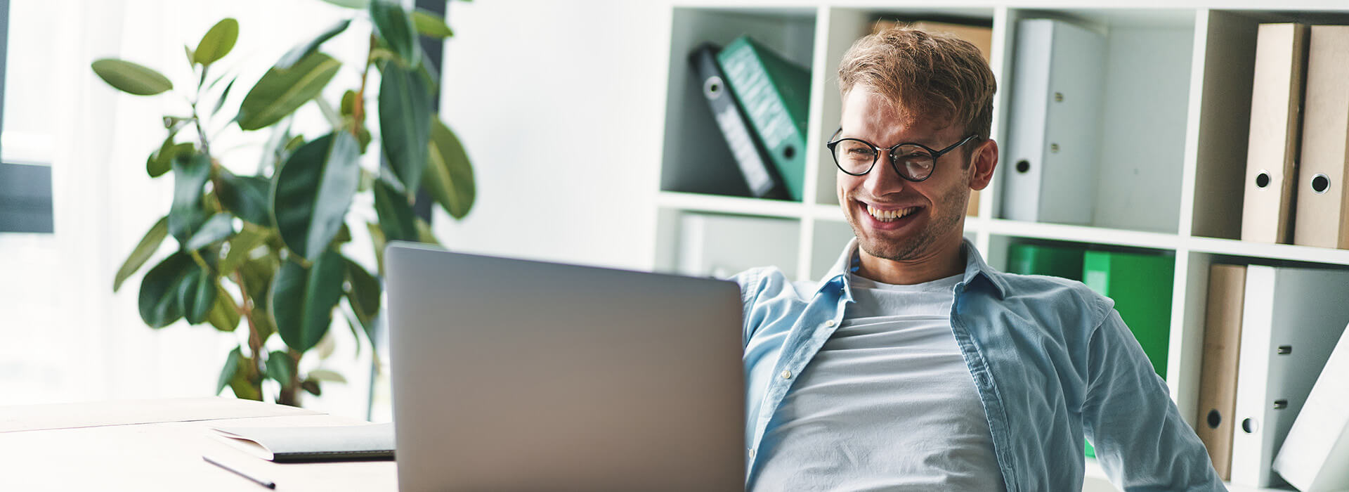 man leaning back in chair laughing at laptop banner