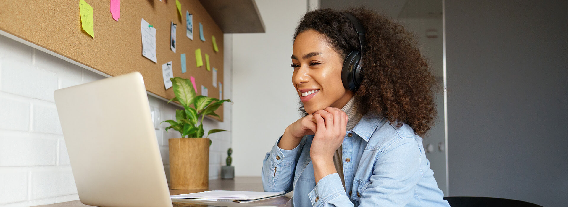 woman wearing a headset smiling at her laptop