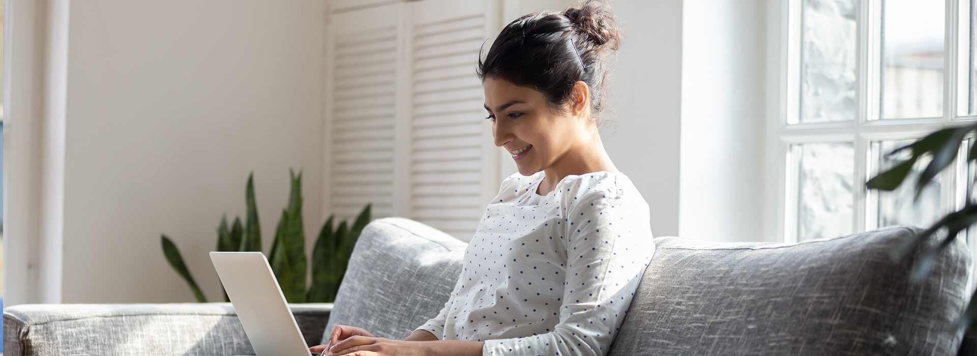 woman sat working on laptop on sofa