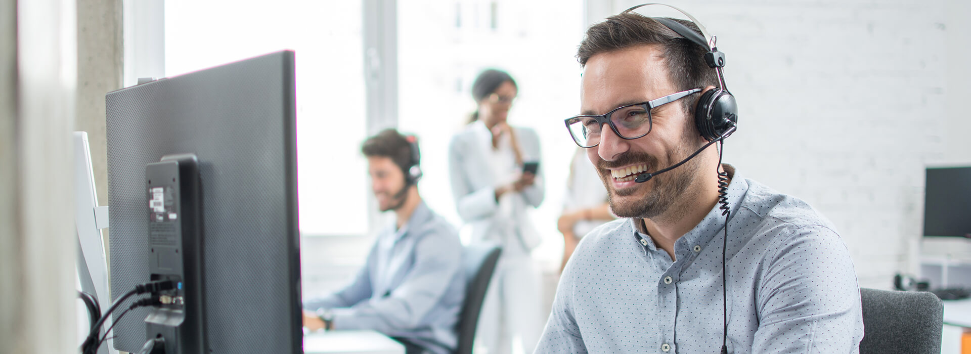 man with headset smiling at computer