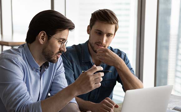 two men talking at a laptop