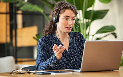 woman talking with headset on at laptop