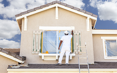 man painting outside of windows