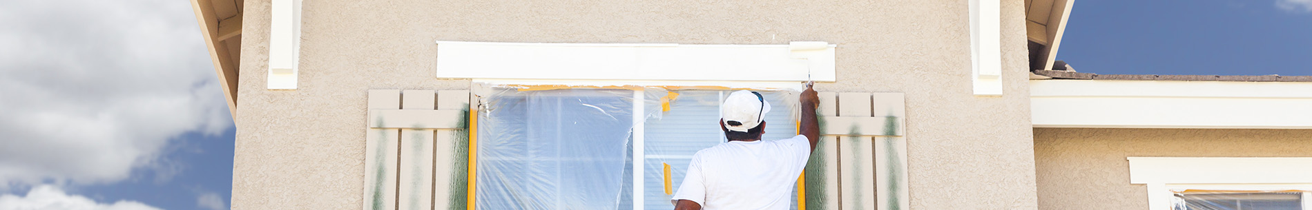 man painting outside of windows