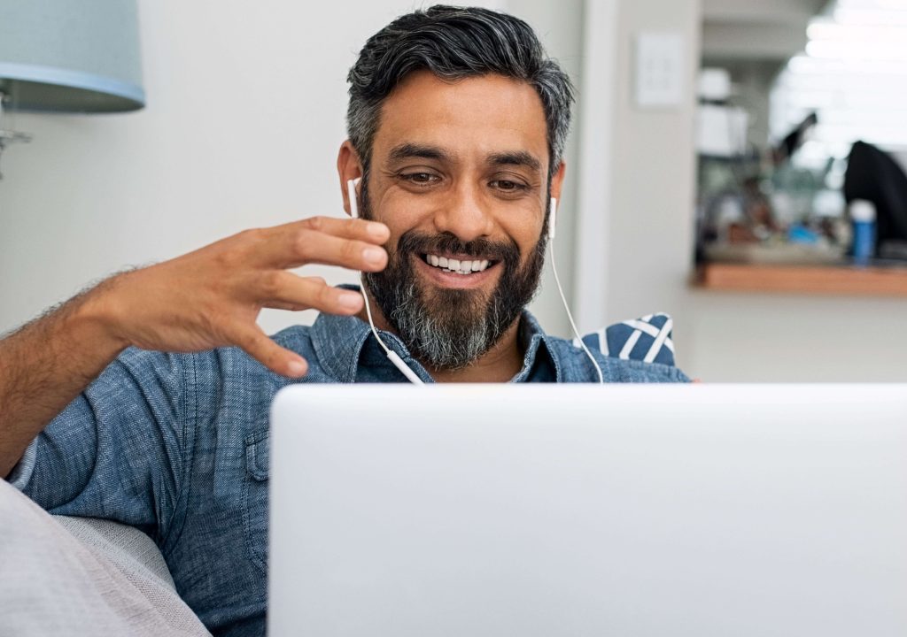 man with headphones in smiling at laptop