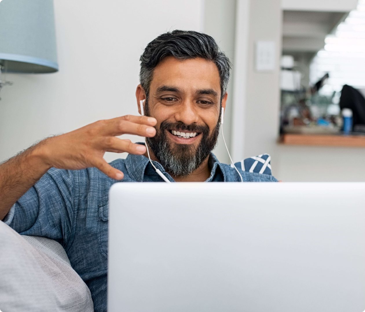 man with headphones in smiling at laptop