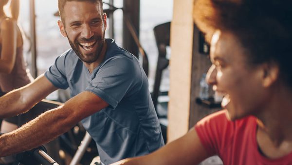 woman and man in gym on exercise bikes