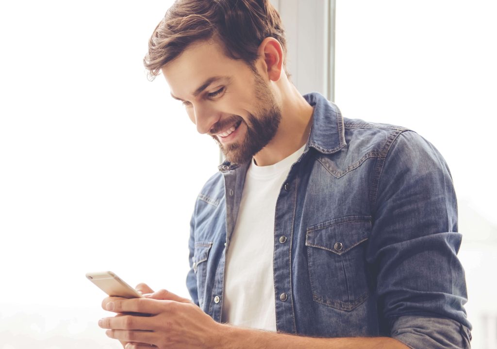 man standing smiling at phone