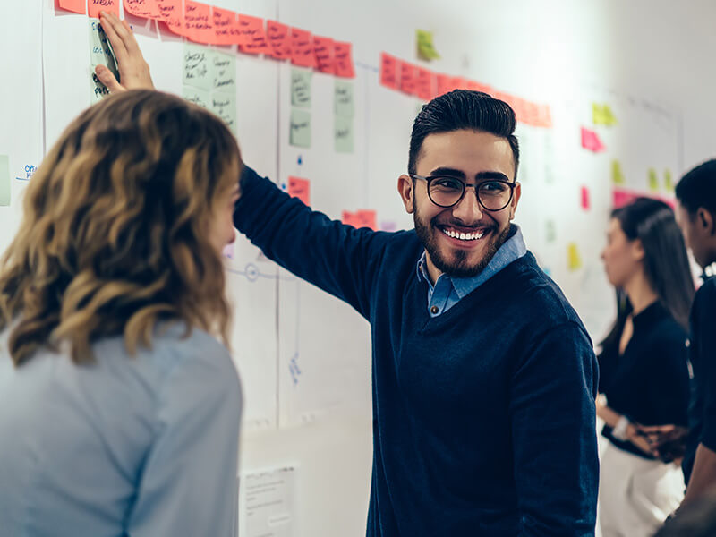 man pointing at whiteboard and smiling