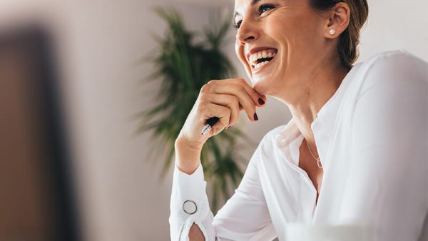 woman laughing while holding pen