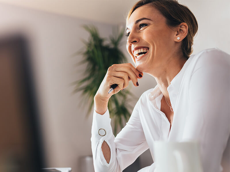 woman laughing while holding pen