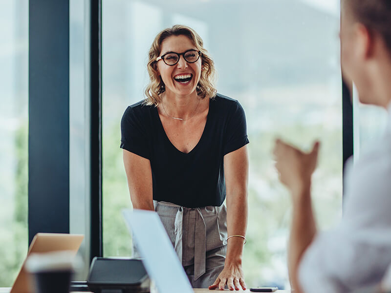 woman laughing with hands on desk