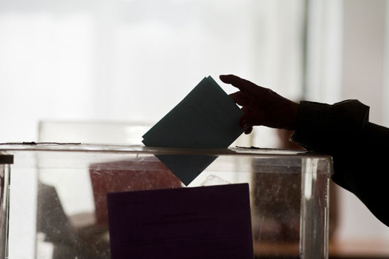 man putting paper slip into ballot box