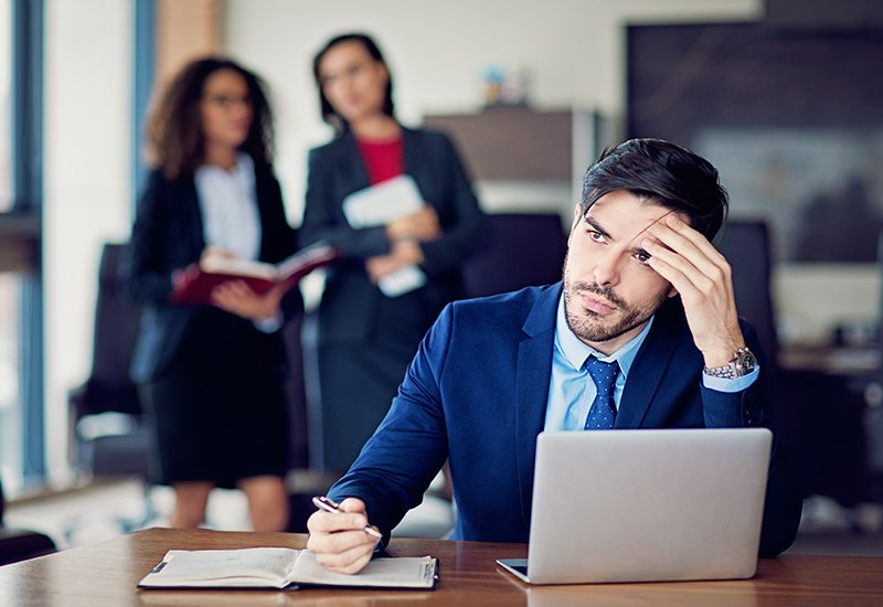 man stressed with women talking about him in the background