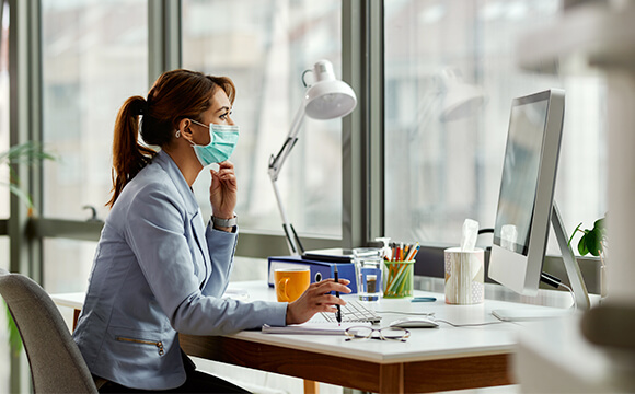 woman wering mask looking at mac