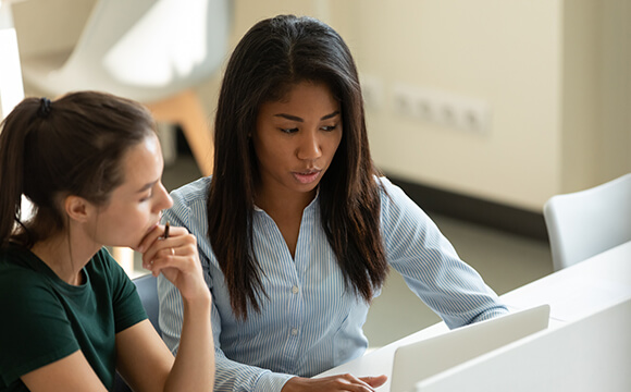 two women talking at laptop