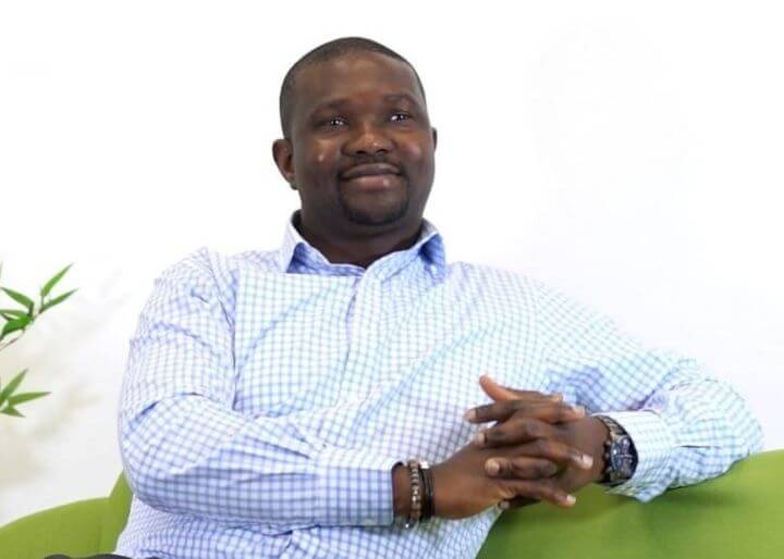 man sat on green sofa smiling