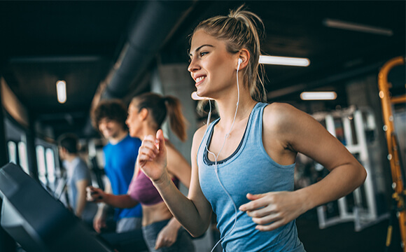 woman with earphones in running on treadmill
