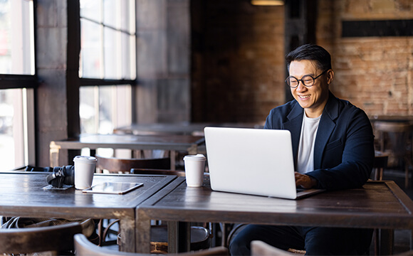 man in cafe smiling at laptop