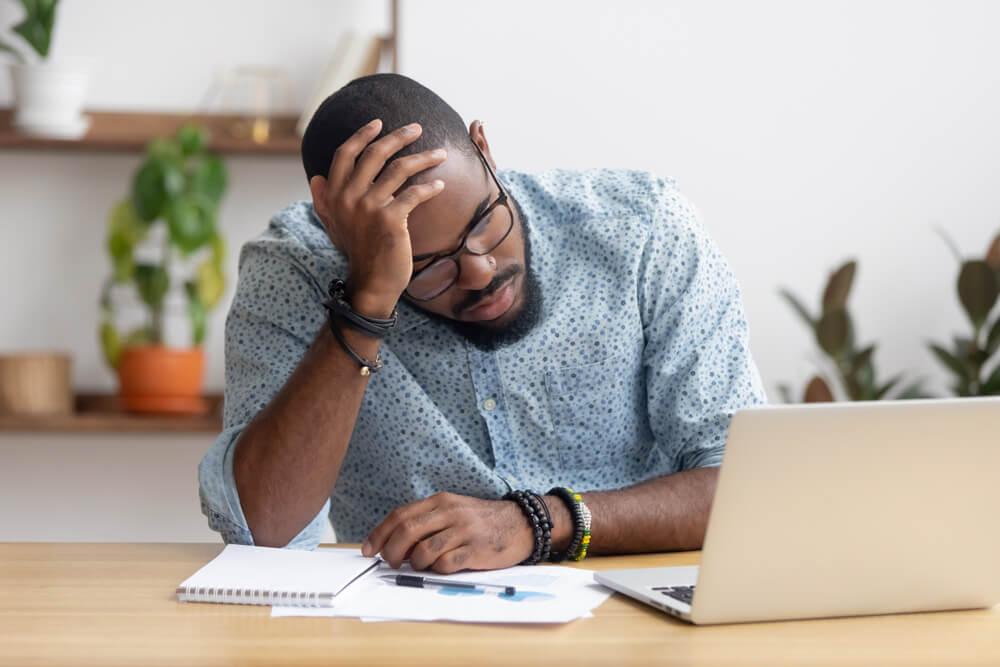 man thinking sat at a laptop