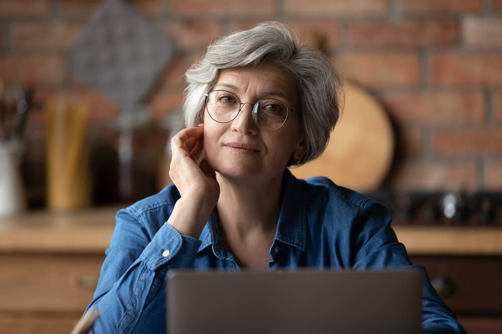 woman sat at laptop looking at camera