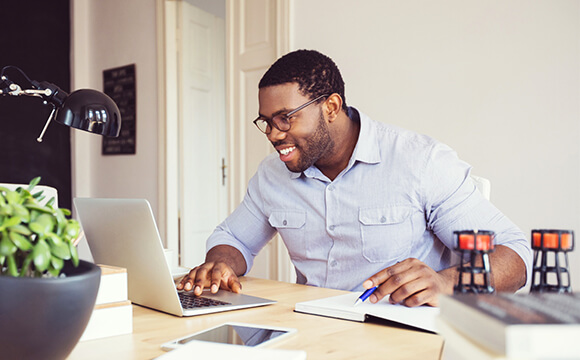 man working at laptop with book