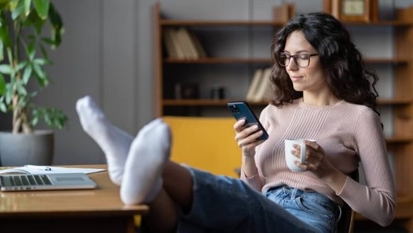 woman relaxing on her phone with feet up on the table
