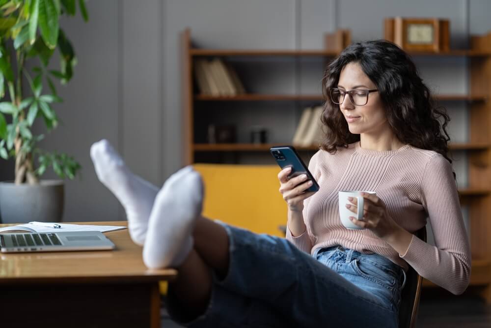 woman relaxing on her phone with feet up on the table