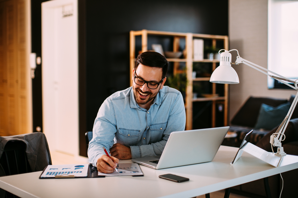 man smiling at notes while writing