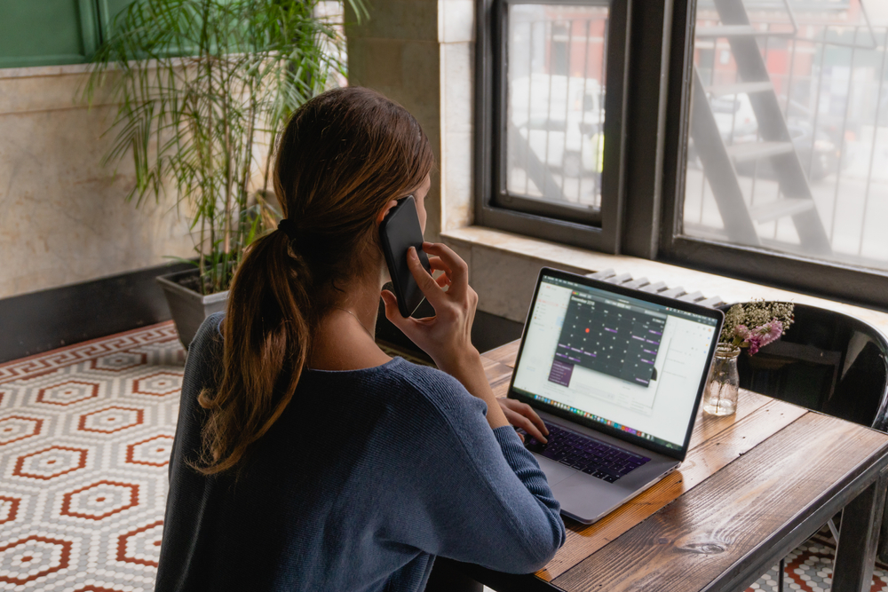 woman on the phone typing on laptop