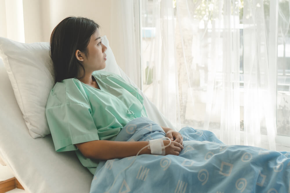 woman staring out of window in hospital bed