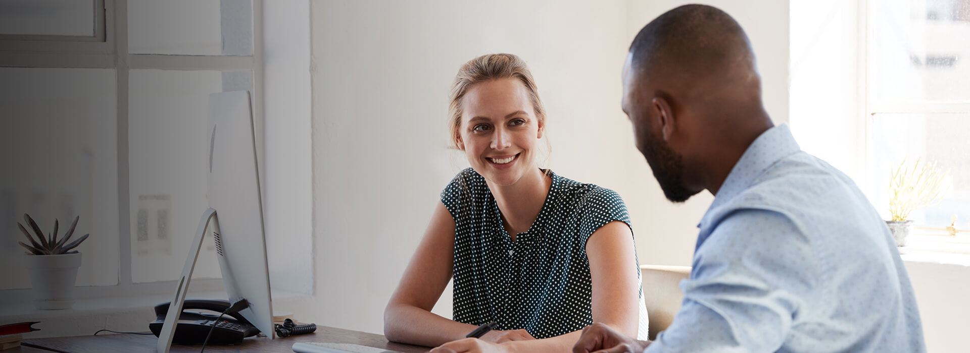 two colleagues talking at desk