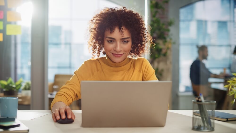woman with curly hair smiling down at laptop