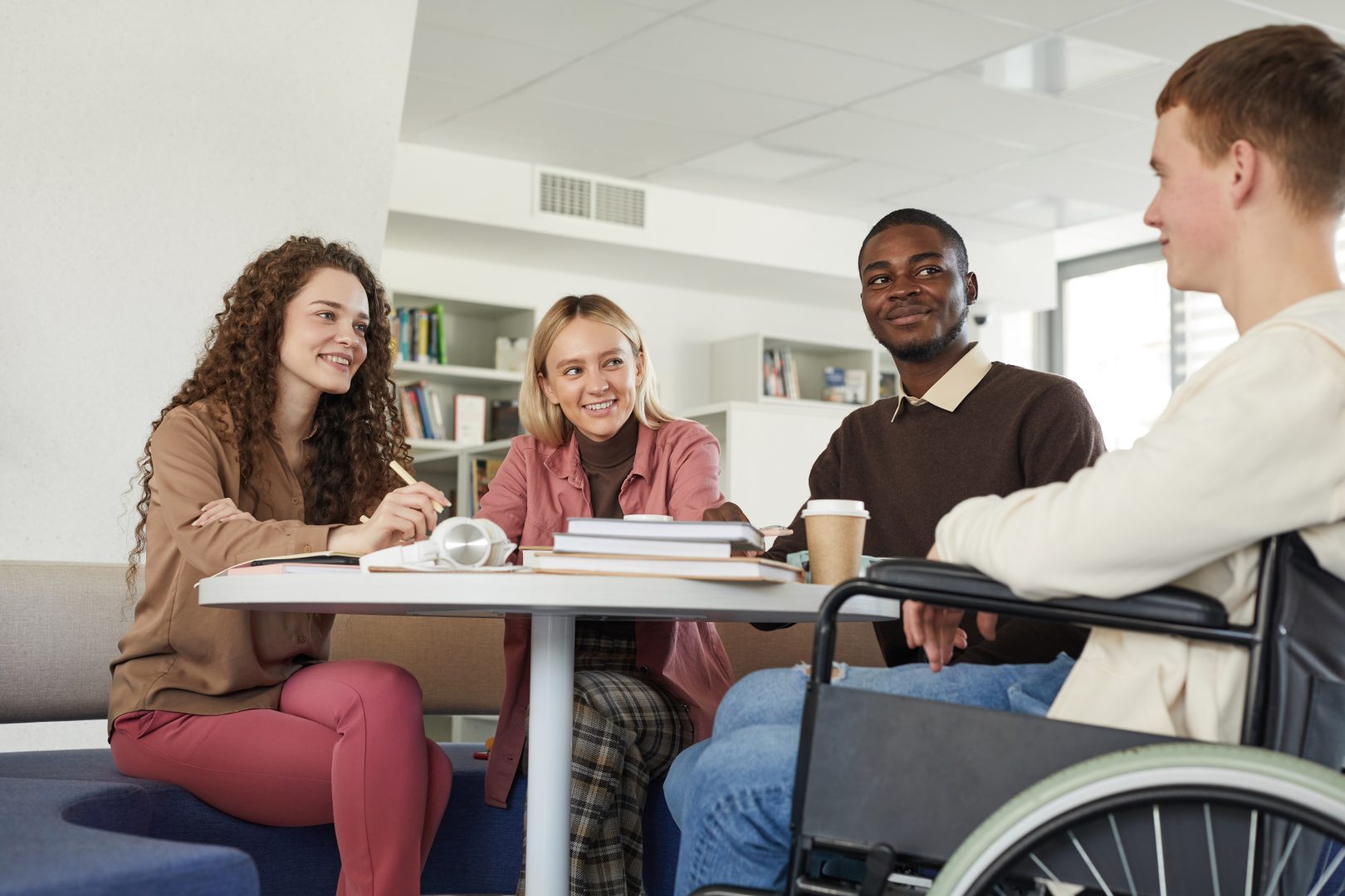 boy in wheelchair speaking with three others at table