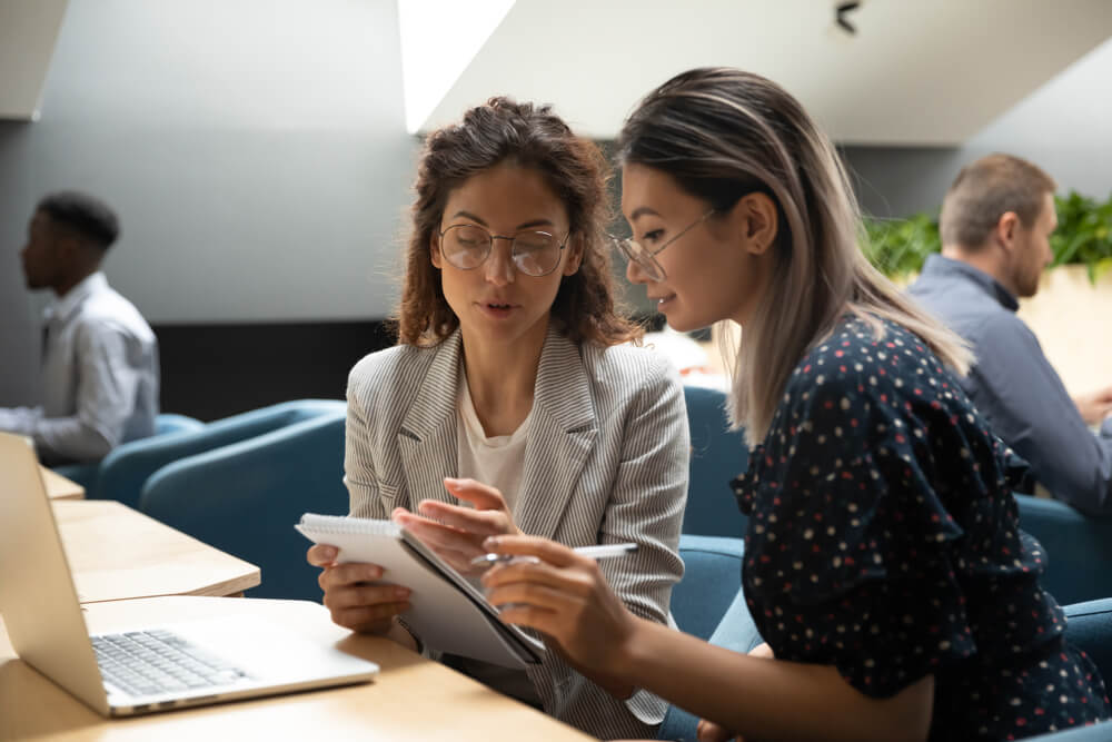 two women discussing notes