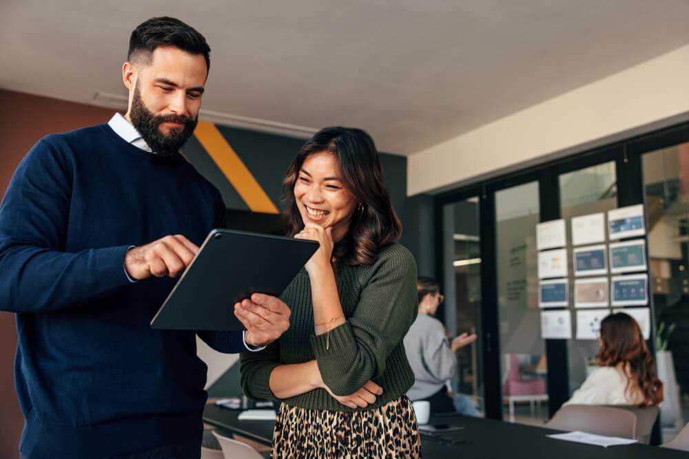 man and woman smiling at tablet