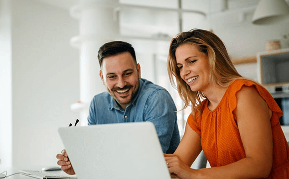 man and woman smiling at a laptop