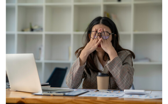 stressed woman rubbing her face under glasses