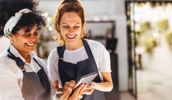 Two female employees smiling at something on a screen.