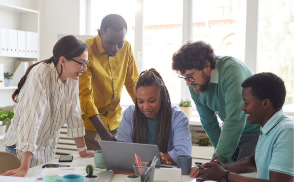 group of people crowded around laptop