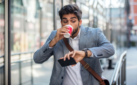 man drinking coffee and checking his watch