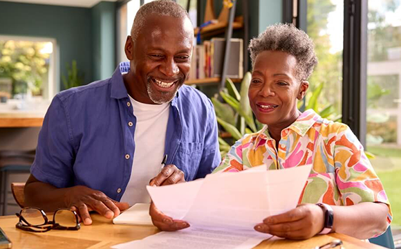 mand and woman sat smiling at papers