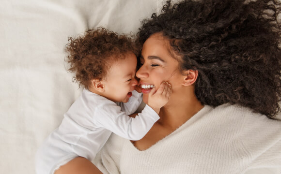 mother and baby smiling at each other laid on bed